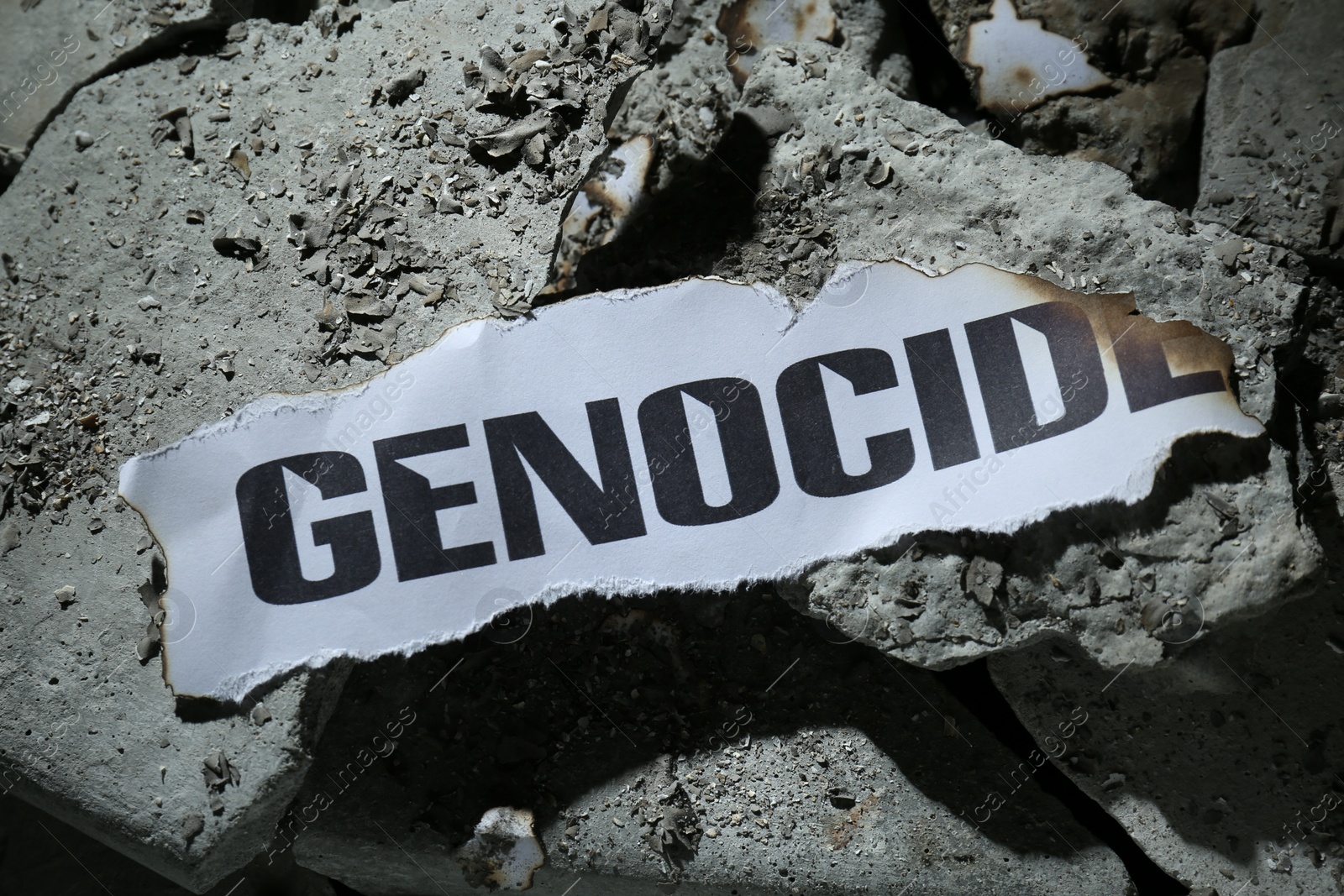 Photo of Paper with word Genocide on pieces of concrete, top view