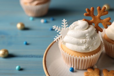 Photo of Tasty Christmas cupcake with snowflakes on light blue wooden table, closeup view. Space for text