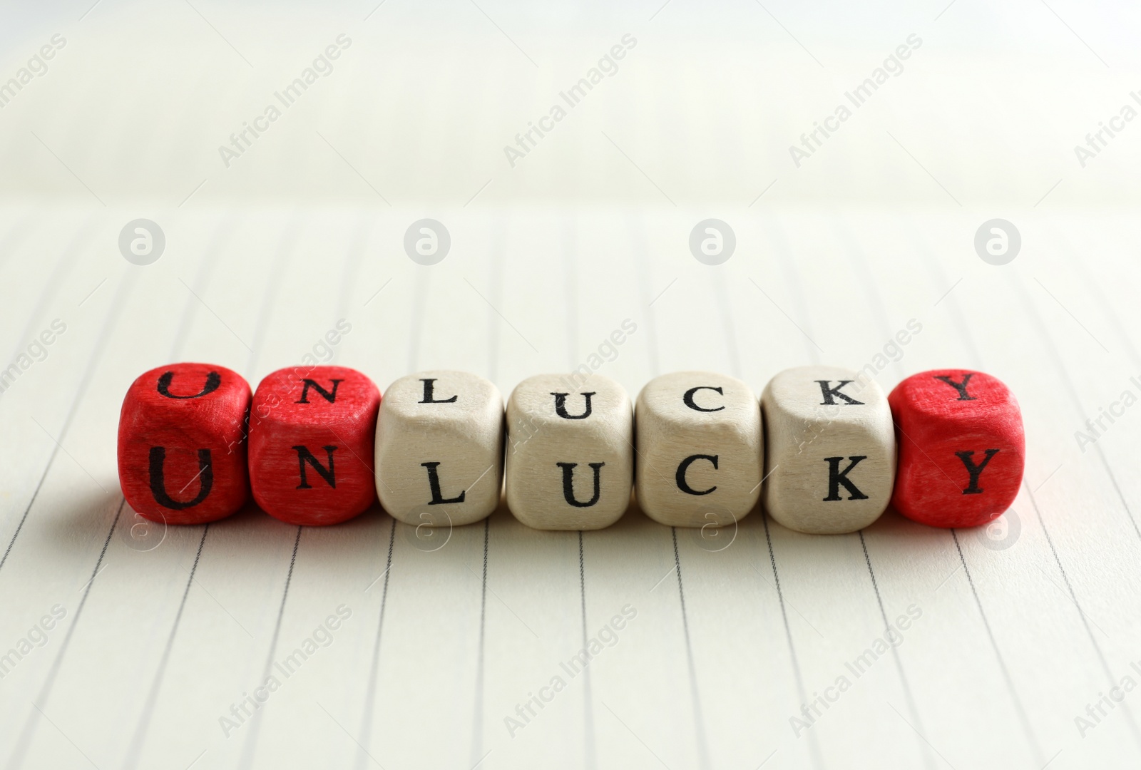 Photo of Red and white cubes with word UNLUCKY on notebook page, closeup