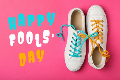 Image of Shoes tied together on pink background, flat lay. Happy Fool's Day