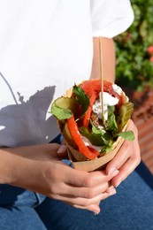 Woman holding wafer with falafel and vegetables outdoors, closeup. Street food