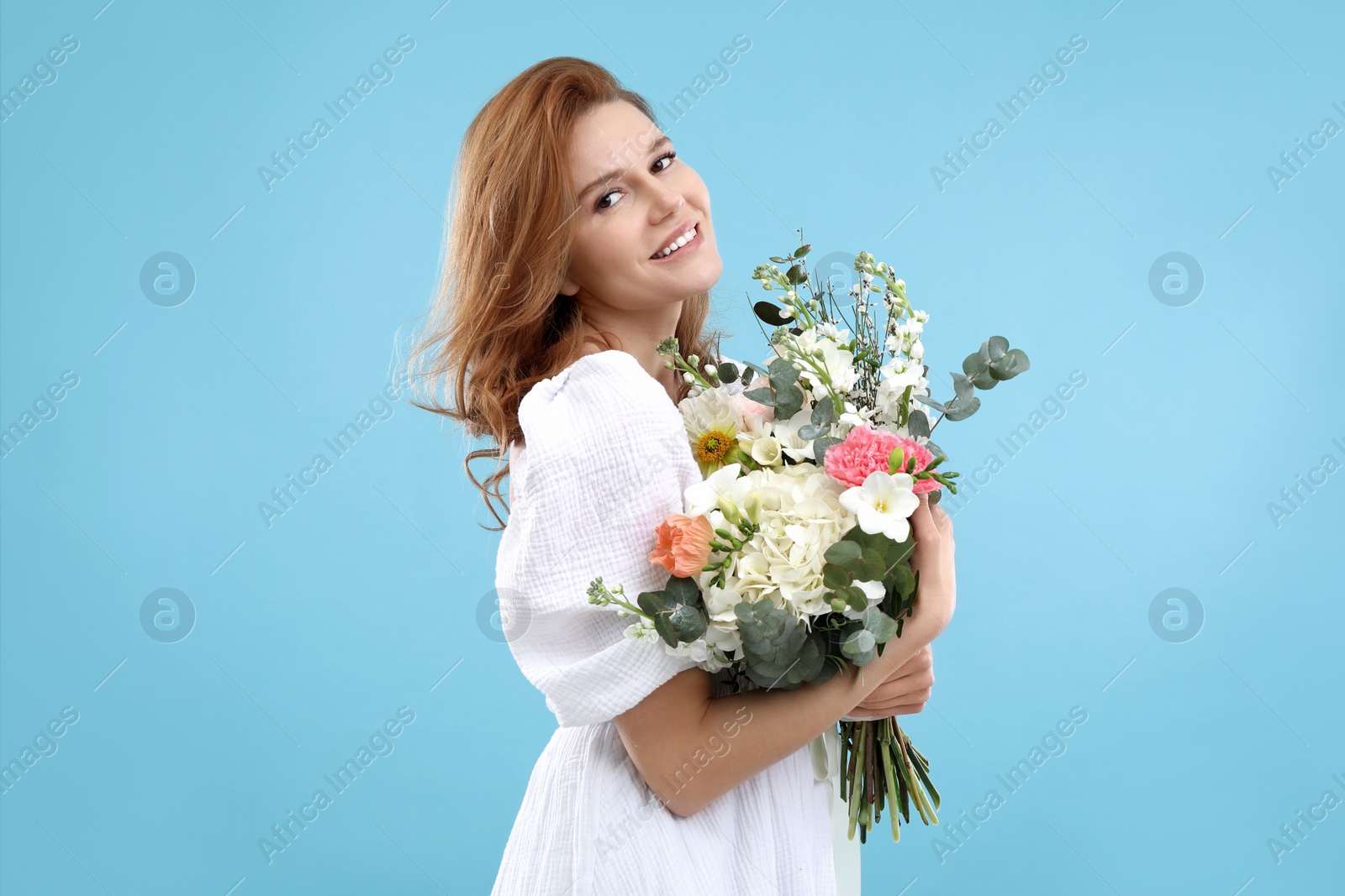 Photo of Beautiful woman with bouquet of flowers on light blue background