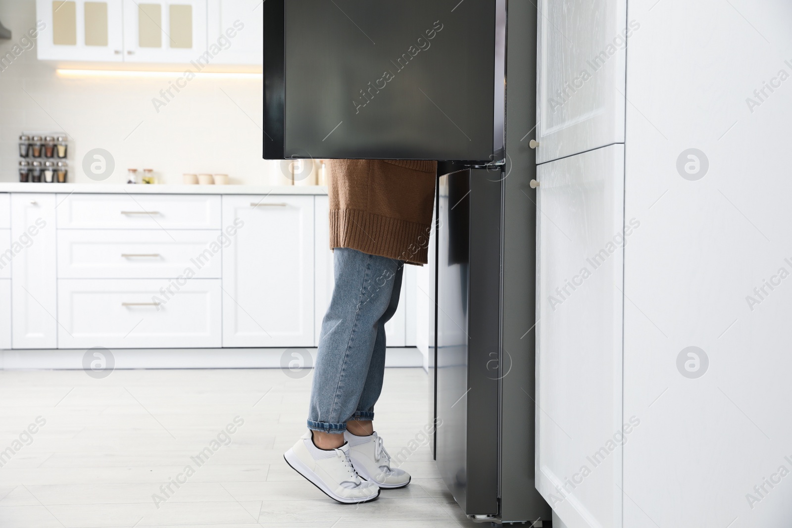 Photo of Young woman looking into refrigerator in kitchen