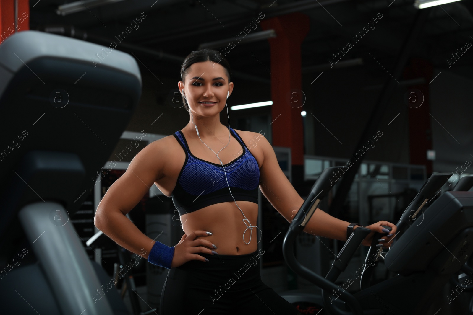 Photo of Young woman working out on elliptical trainer in modern gym