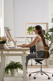 Young woman working on computer at table in room