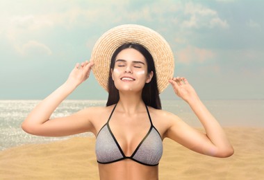 Image of Sun protection. Beautiful young woman with sunblock on her face near sea
