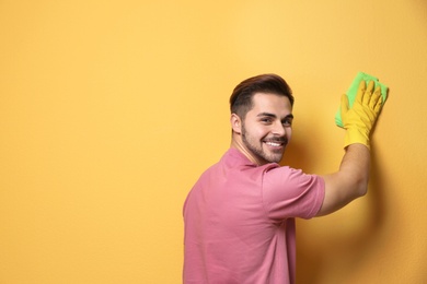 Photo of Man cleaning color wall with rag. Space for text