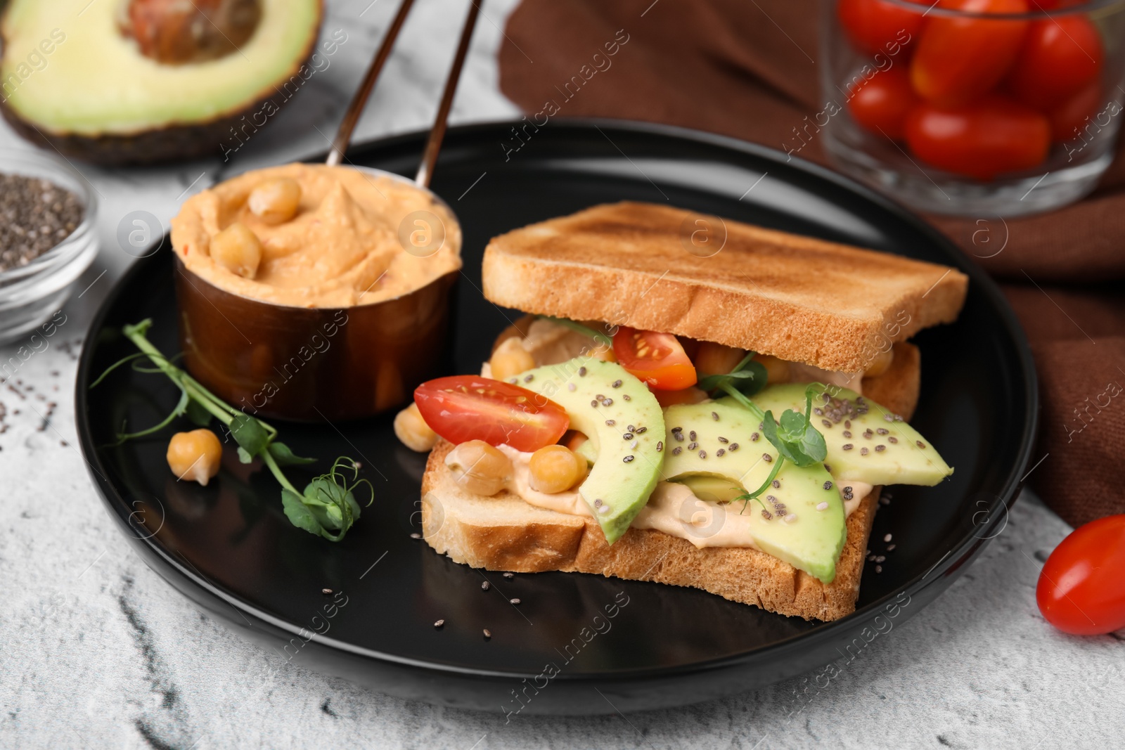 Photo of Delicious sandwich with hummus and vegetables on white textured table, closeup