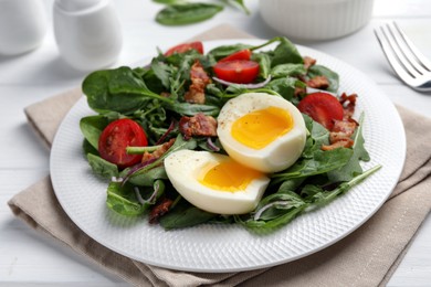 Delicious salad with boiled egg, bacon and tomatoes on white wooden table, closeup