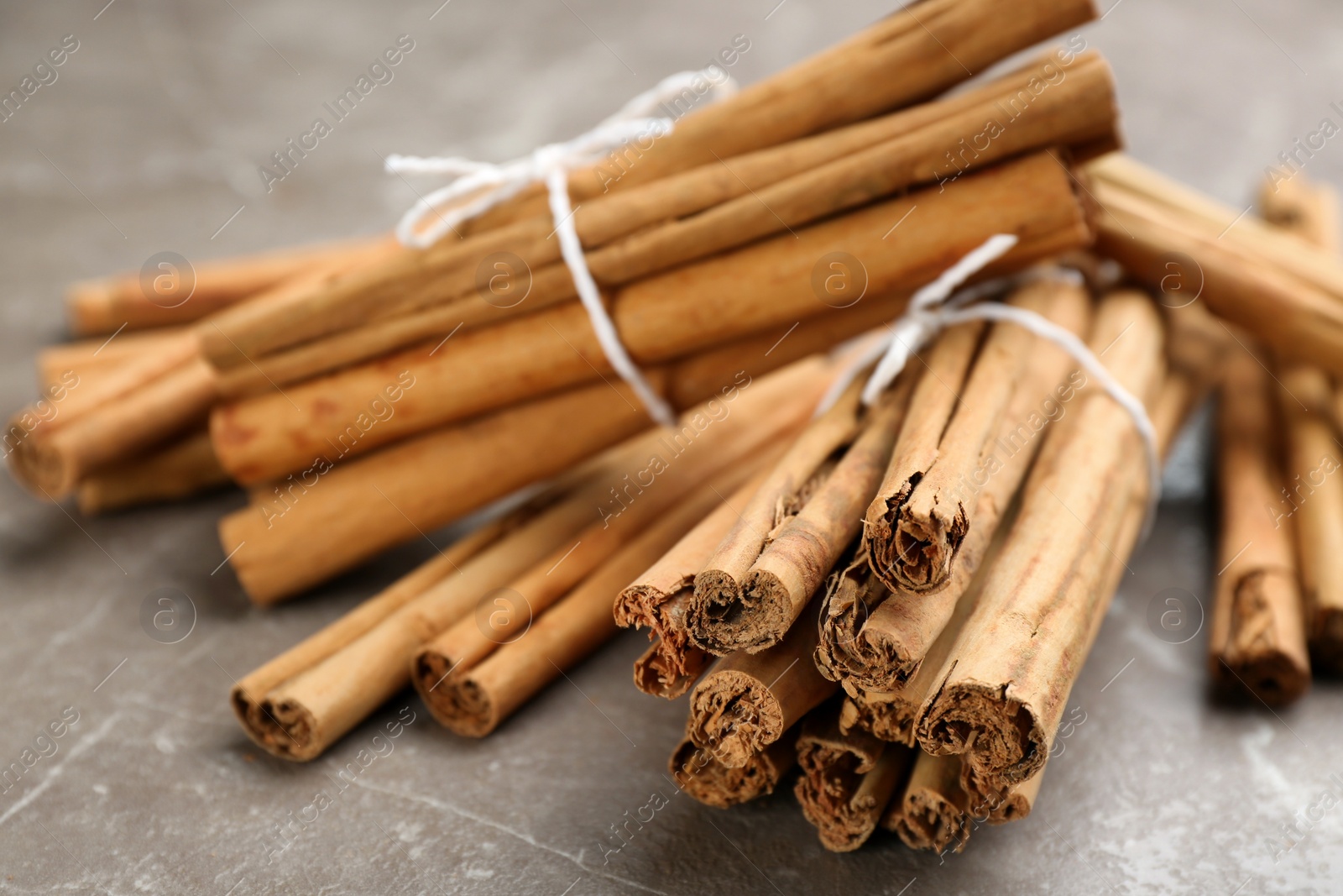 Photo of Aromatic cinnamon sticks on grey table, closeup