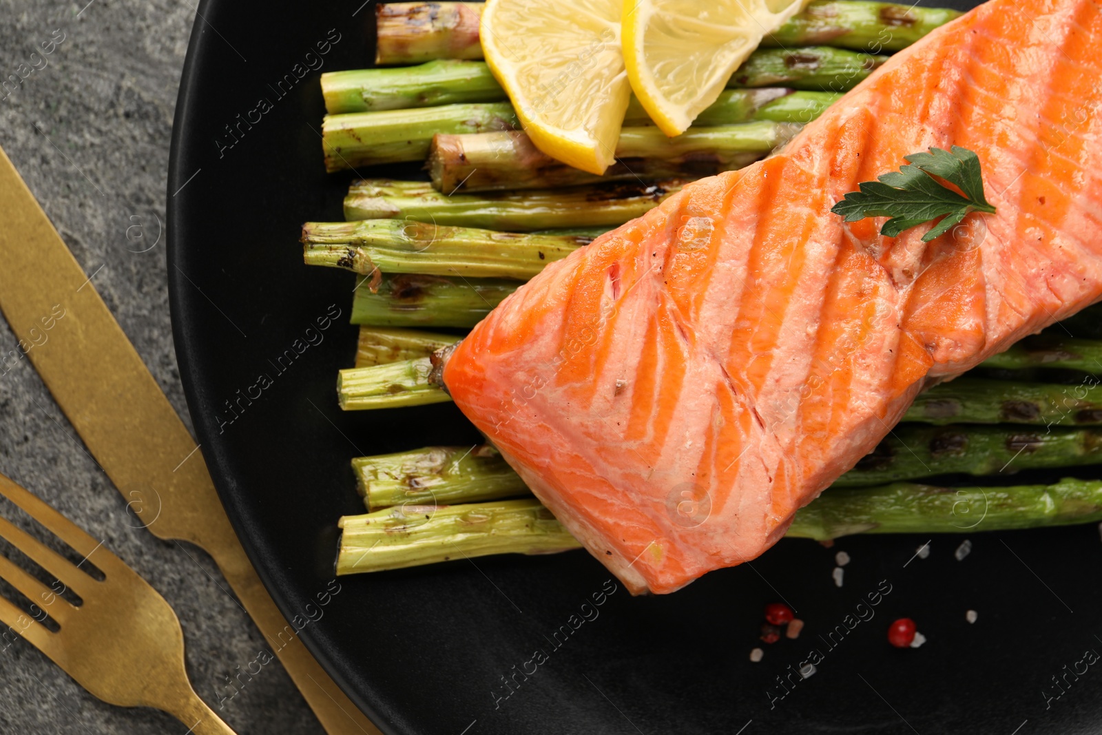Photo of Tasty grilled salmon with asparagus, lemon and spices served on table, flat lay