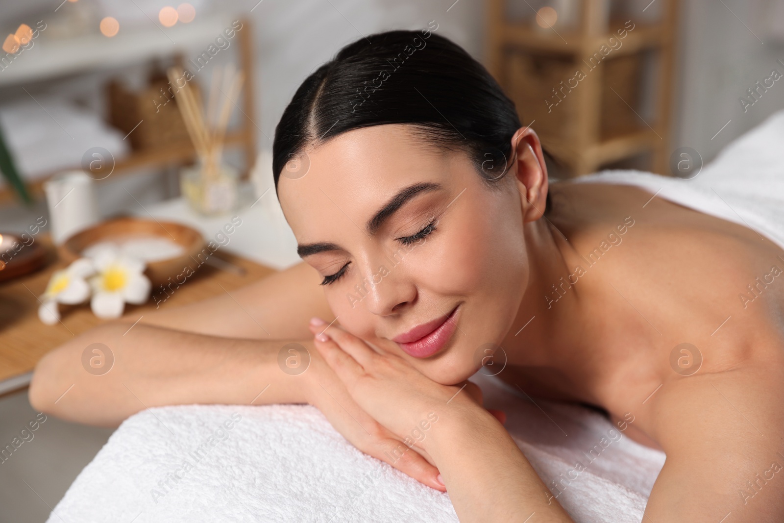 Photo of Beautiful woman relaxing on massage table in spa salon