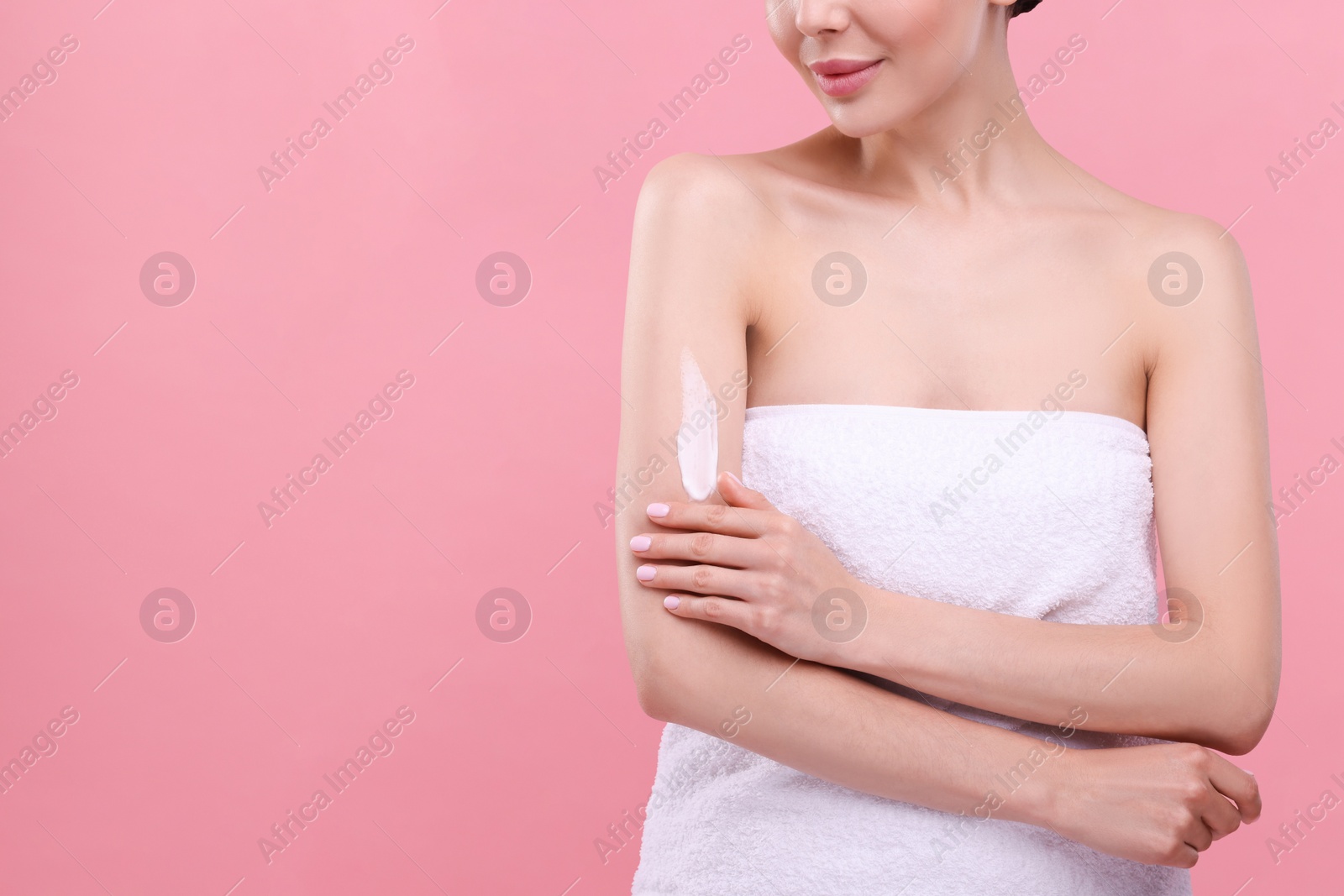 Photo of Woman with smear of body cream on her arm against pink background, closeup. Space for text