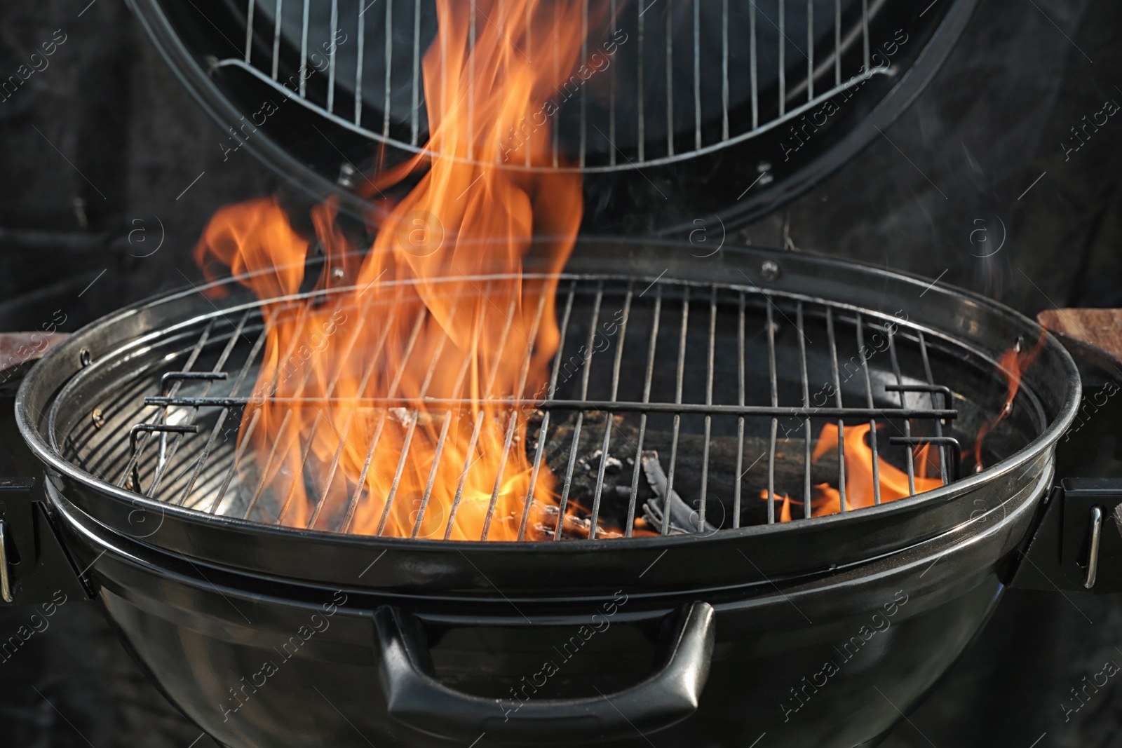 Photo of New modern barbecue grill with burning firewood, closeup