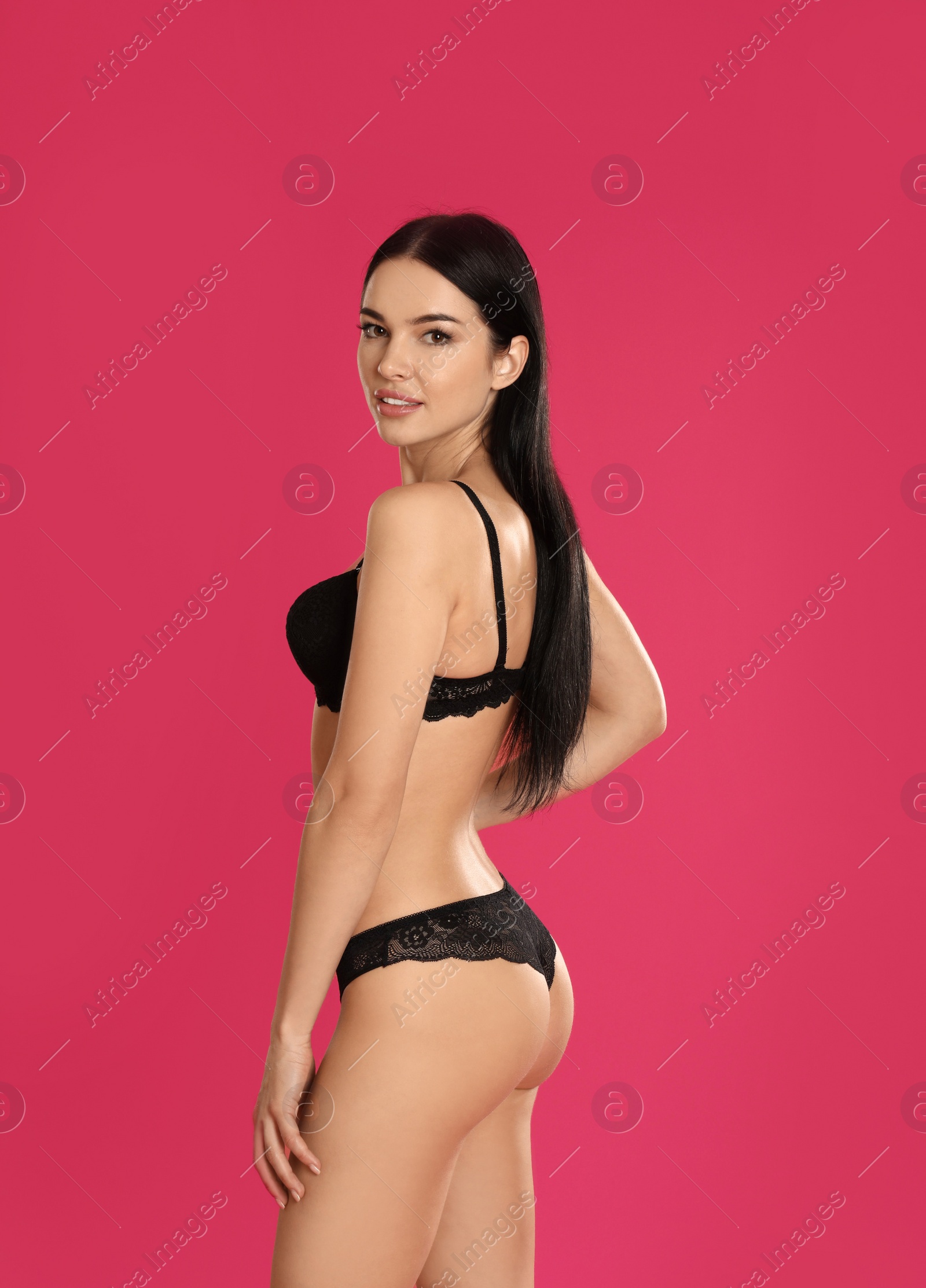 Photo of Beautiful young woman in black underwear on pink background