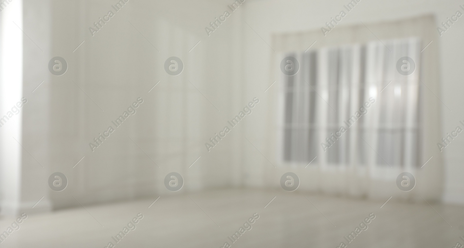 Photo of Empty room with white walls and large window, blurred view