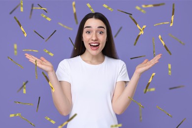 Happy woman and flying confetti on violet background