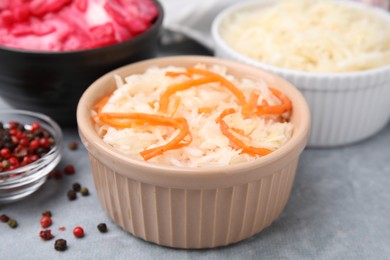 Photo of Delicious sauerkraut prepared according to different recipes on light gray table, closeup