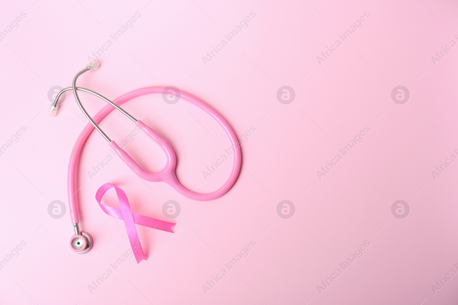 Photo of Pink ribbon and stethoscope on color background, top view with space for text. Breast cancer concept