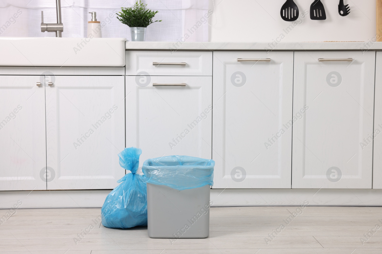 Photo of Plastic garbage bag and trash can in kitchen, space for text