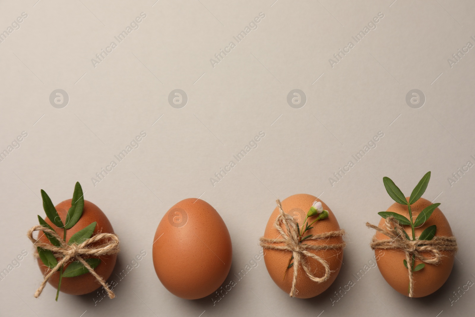 Photo of Festively decorated chicken eggs on light grey background, flat lay with space for text. Happy Easter