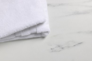 Photo of Clean folded towel on white marble table, space for text