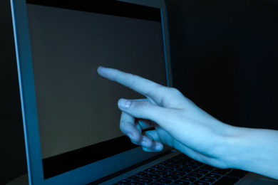Woman using laptop on dark background, closeup