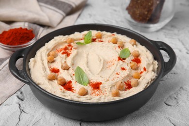 Photo of Delicious hummus with chickpeas and paprika served on white textured table, closeup
