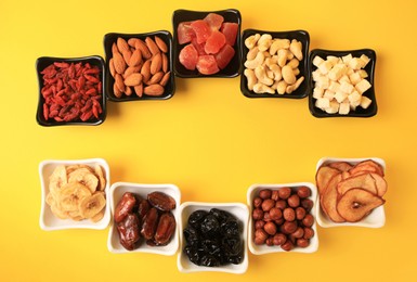 Photo of Bowls with dried fruits and nuts on yellow background, flat lay. Space for text