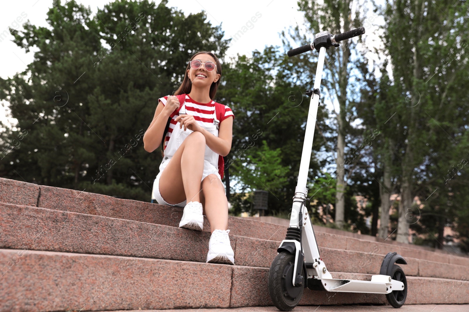 Photo of Young woman with electric kick scooter on stairs outdoors
