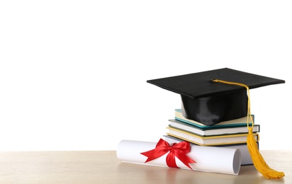 Photo of Graduation hat with books and diploma on table against white background