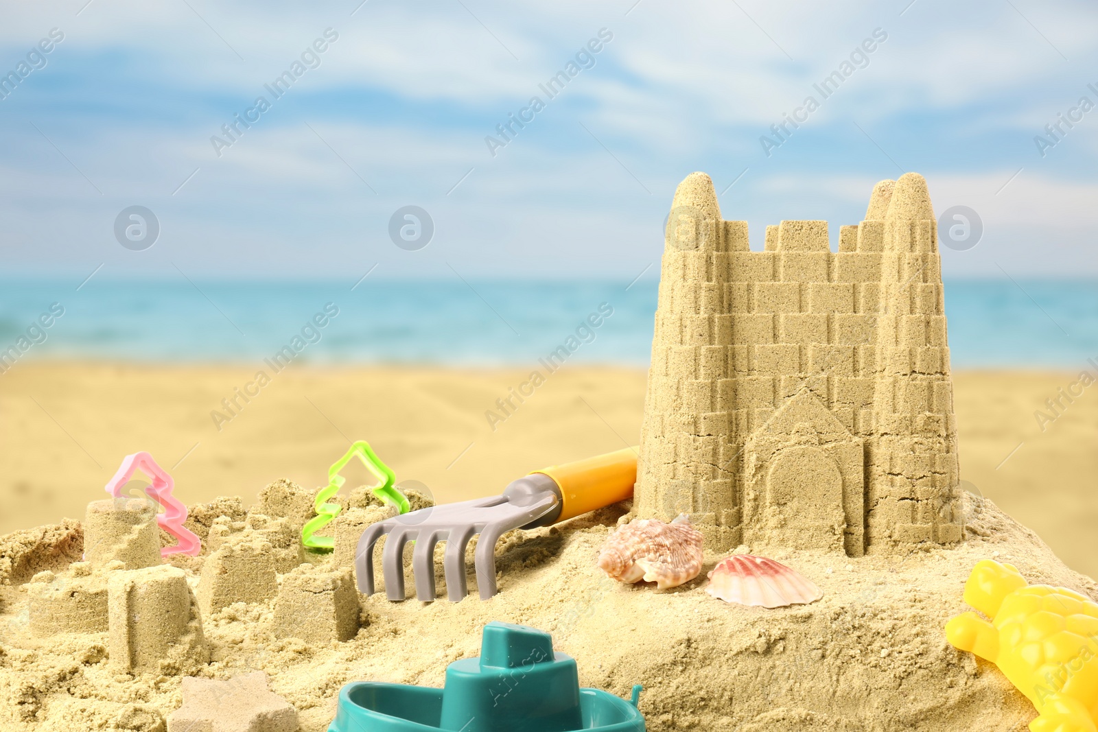 Image of Sand castle with toys on ocean beach. Outdoor play