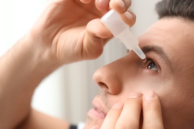 Photo of Man using eye drops on blurred background, closeup