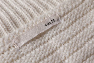 Clothing label on beautiful beige garment, closeup