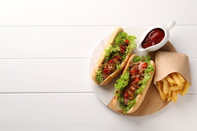 Photo of Tasty hot dogs with chili, lettuce, ketchup and French fries on white wooden table, top view. Space for text