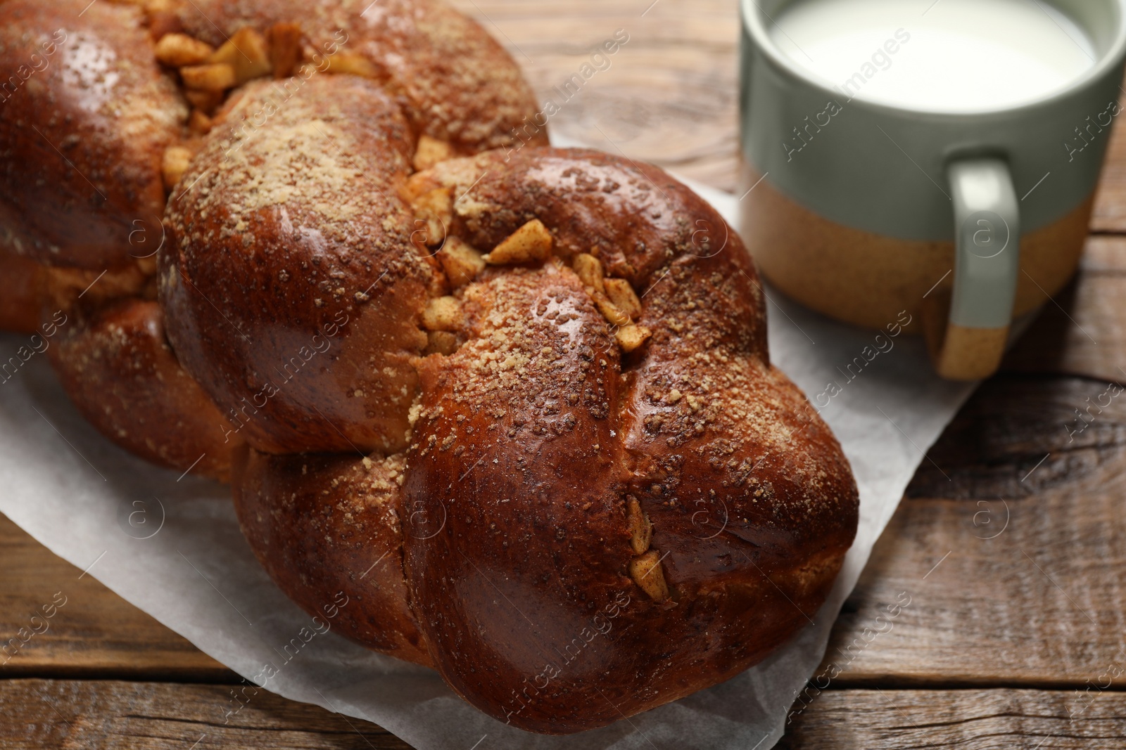 Photo of Delicious yeast dough cake and cup of milk on wooden table, closeup