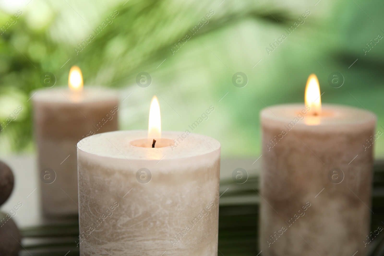 Photo of Burning aromatic candles on blurred green background