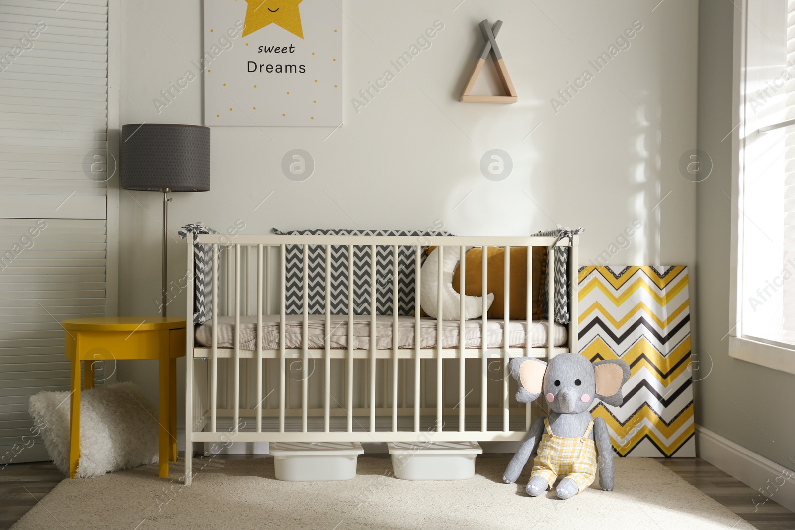 Photo of Cute baby room interior with crib and decor elements