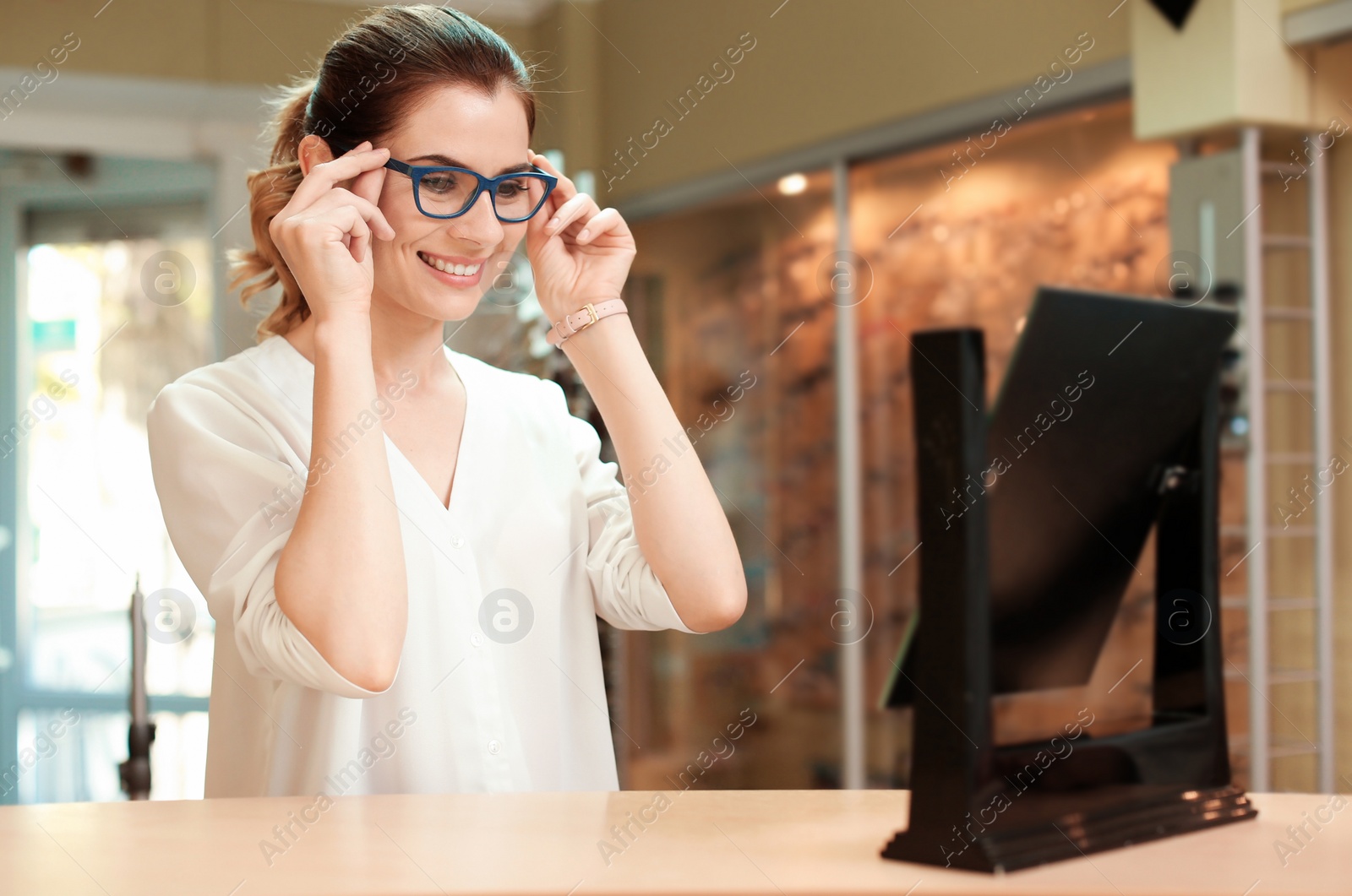 Photo of Young woman trying on glasses in optical store. Ophthalmologist prescription