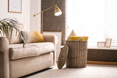 Basket with soft plaid and pillows in living room interior