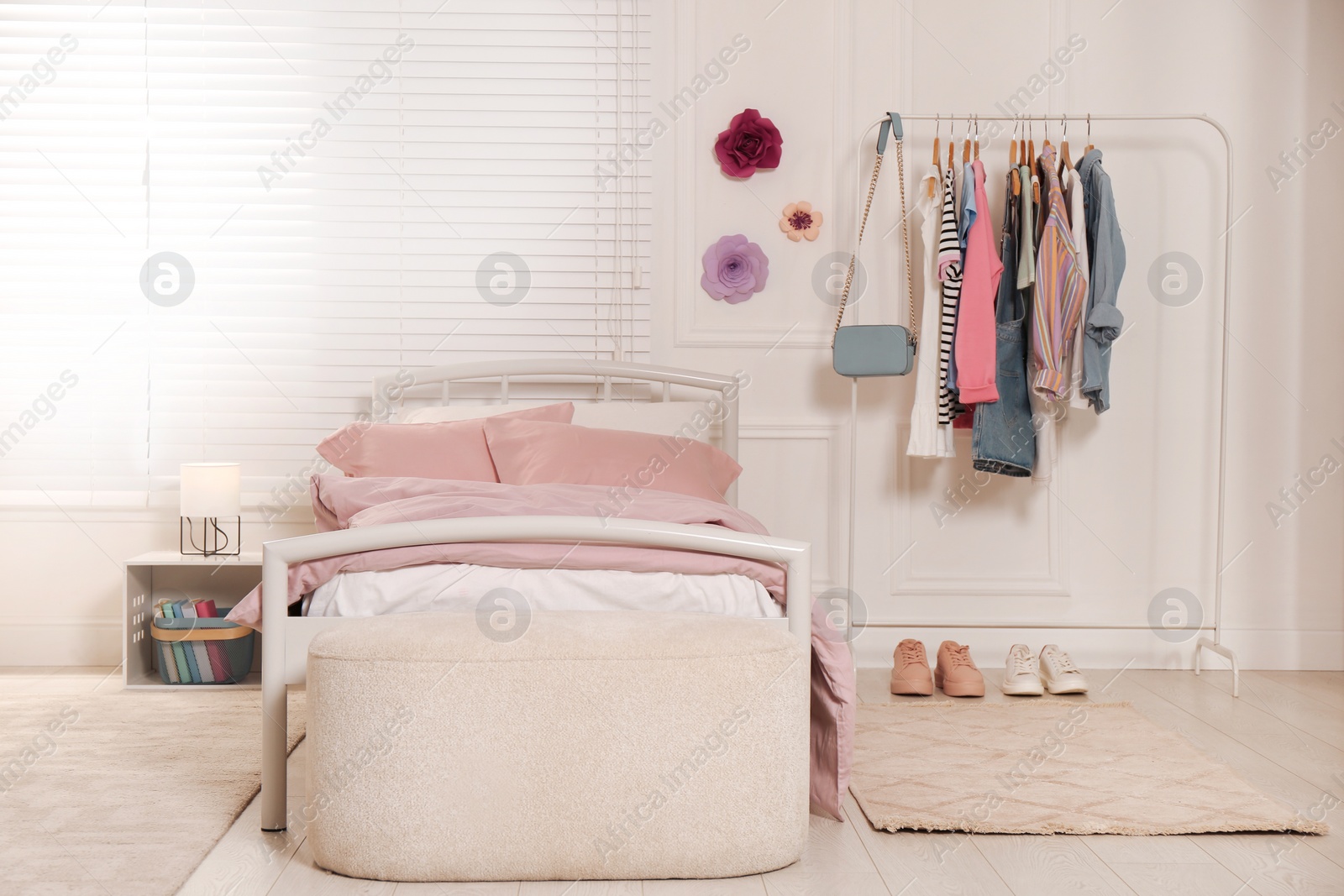 Photo of Stylish teenager's room interior with comfortable bed and clothing rack