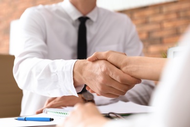 Photo of Business partners shaking hands at table after meeting in office, closeup