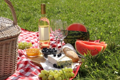 Photo of Picnic blanket with delicious food and wine outdoors on summer day