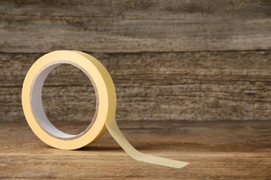 Photo of Roll of adhesive tape on wooden table, space for text