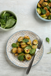 Photo of Delicious roasted brussels sprouts with basil served on white wooden table, flat lay