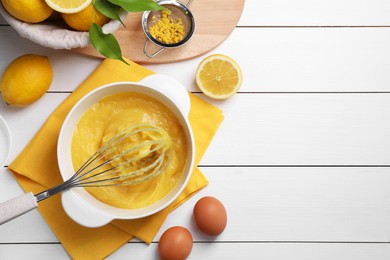 Photo of Delicious lemon curd in bowl, ingredients, whisk and sieve on white wooden table, flat lay. Space for text