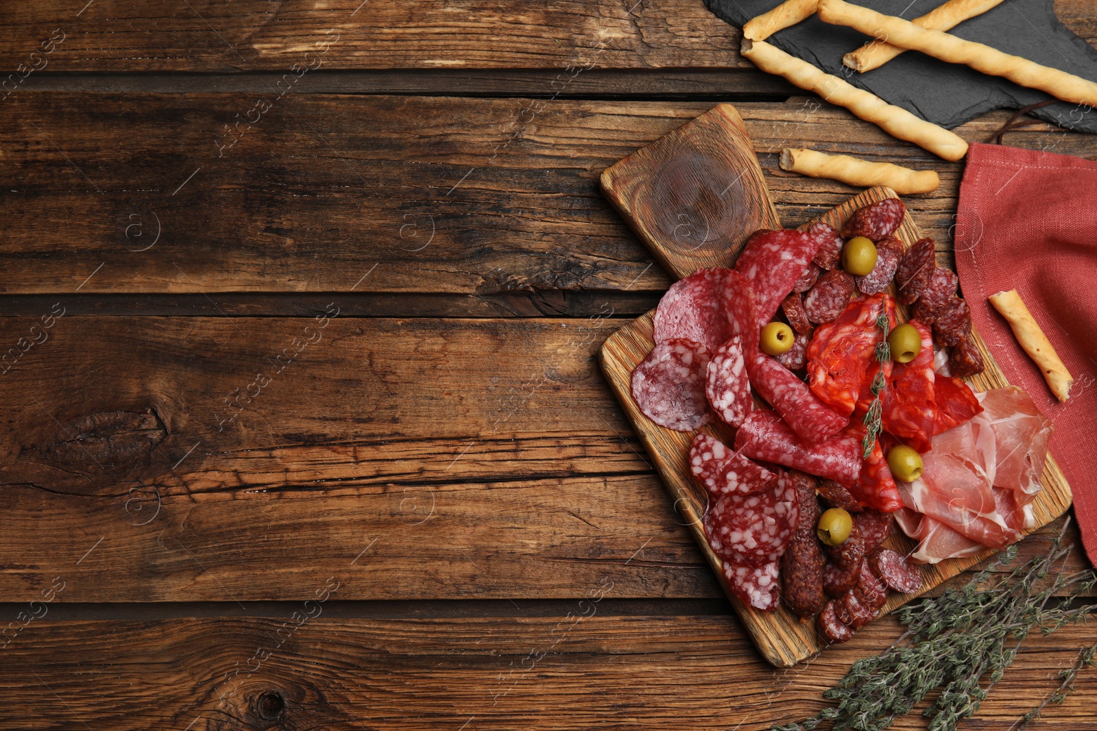 Photo of Tasty prosciutto with other delicacies served on wooden table, flat lay. Space for text