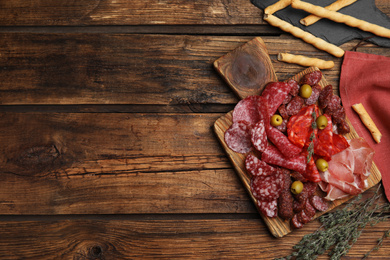 Photo of Tasty prosciutto with other delicacies served on wooden table, flat lay. Space for text