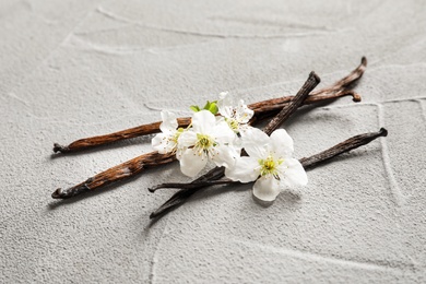 Vanilla sticks and flowers on light background