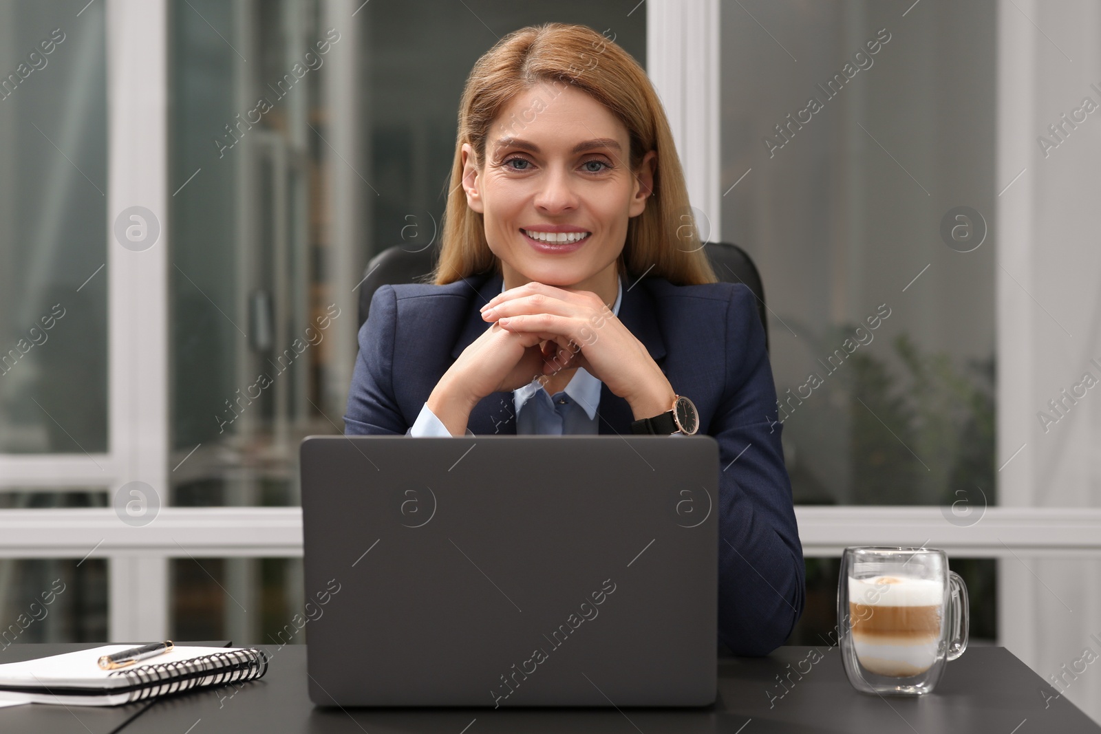 Photo of Woman working on laptop at black desk in office